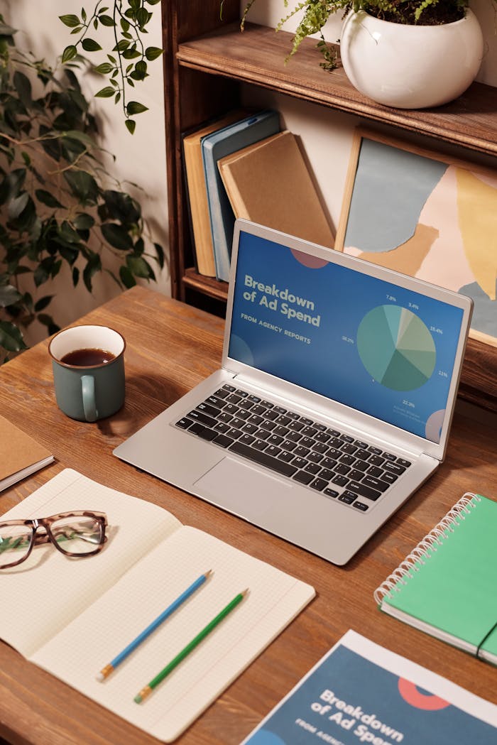 Mastering the First Impression: Your intriguing post title goes here Laptop displaying ad spend data on a wooden desk with office supplies.